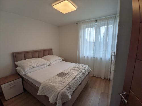 um quarto com uma cama com lençóis brancos e uma janela em Ika LuX apartmani 4* em Sjenica