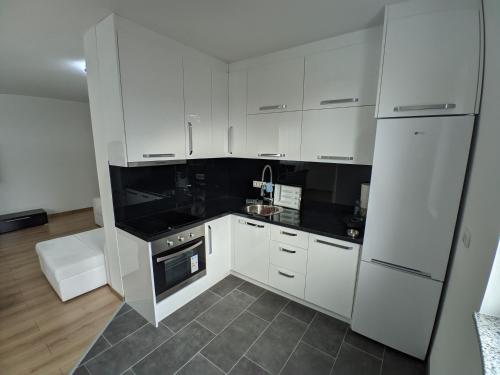 a kitchen with white cabinets and black counter tops at Ika LuX apartmani 4* in Sjenica