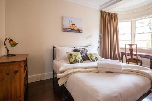 um quarto com 2 camas, uma secretária e uma janela em Joli Light Filled Delight Close to the MCG em Melbourne