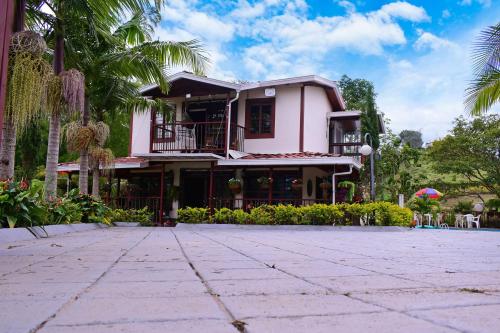 una casa rosa con un patio frente a ella en Finca en Guatapé a solo minutos de la piedra, con Jacuzzi & piscina en El Peñol