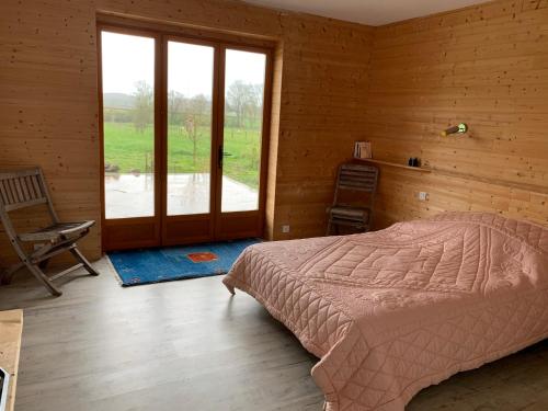 ein Schlafzimmer mit einem Bett und einem großen Fenster in der Unterkunft Chambre d'hôtes dans les champs in Jeux-lès-Bard