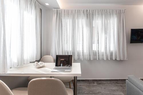 a room with a table with a laptop and chairs at Mariet Naxos Elegant Suites in Naxos Chora