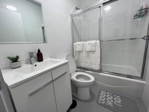 ein weißes Bad mit einem WC und einer Dusche in der Unterkunft Modern 2 bedroom apt w pool table in Heart of BKLYN in Brooklyn