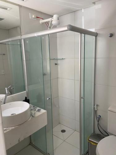 un bagno con doccia in vetro e lavandino di Apart. Dois quartos na Ponta Verde a Maceió