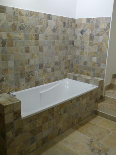a bath tub in a bathroom with a tile wall at Le Mas d'Isnard in Arles