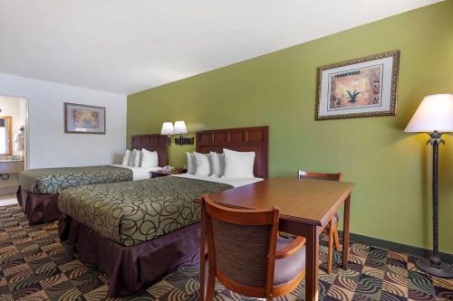 a hotel room with two beds and a table at Best Western Caprock Inn in Brownfield