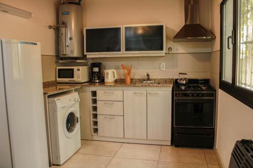 a kitchen with white cabinets and a washer and dryer at Departamento Parras del Abuelo 2 in Malargüe