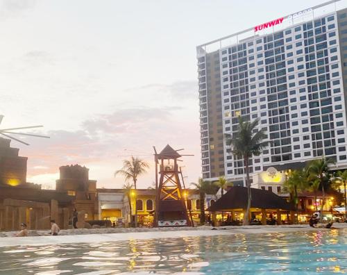a pool in front of a building with a clock tower at Sunway City Onsen COSY HOME Tambun Ipoh in Ipoh