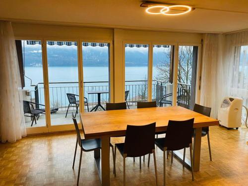 ein Esszimmer mit einem Tisch und Stühlen sowie einem Balkon in der Unterkunft Lake View Apartment - 12 in Niederried
