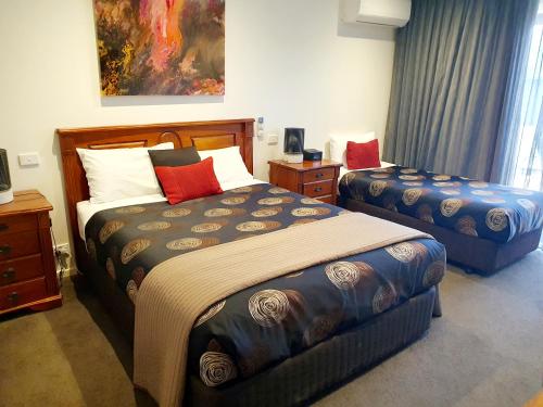 a bedroom with two beds and a painting on the wall at Addison Motor Inn in Shepparton