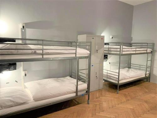 a room with three bunk beds with white sheets at GLOBE Hostel Prague ADULTS ONLY in Prague