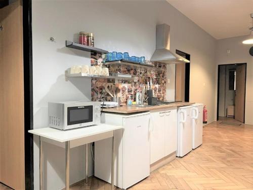 a kitchen with white cabinets and a microwave on a counter at GLOBE Hostel Prague ADULTS ONLY in Prague