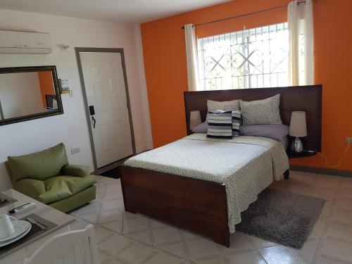 a bedroom with a bed and a chair and a window at JUS4U-Apt-3 The Home Away From Villa in Ocho Rios