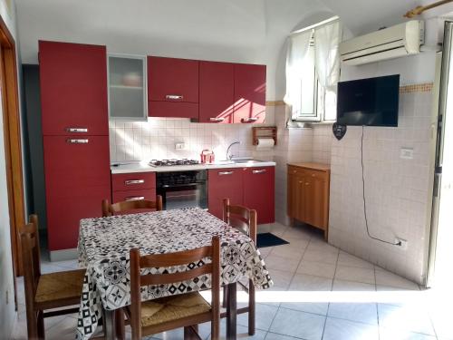 une cuisine avec des placards rouges et une table avec des chaises dans l'établissement Casa Bona Furtuna, à Catane