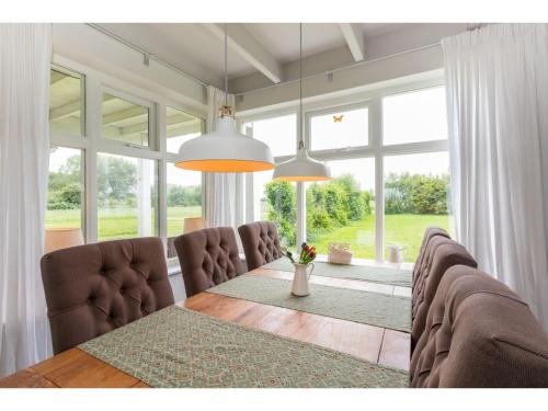Un comedor con mesa y sillas y ventanas. en Family House in Vrouwenpolder near Beach, en Vrouwenpolder