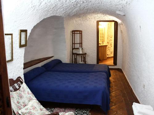 a bedroom with a blue bed and a doorway at Rustic Cave House in Alcudia de Guadix with Pool in Alcudia de Guadix