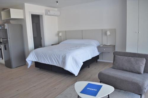 a bedroom with a bed and a couch and a chair at SYRAH Premium B2 - Piscina privada con vista al mar by depptö in Punta del Este