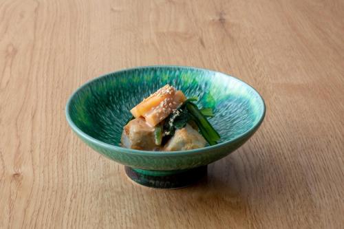 a blue bowl of food on a wooden table at Sensui in Toyooka