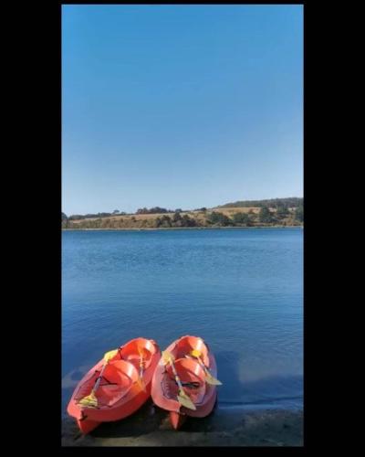 two pink kayaks sitting on top of a body of water at Cabaña en Playa Hermosa in Pichilemu