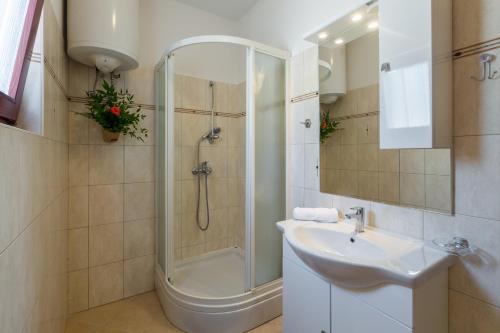 ein Bad mit einer Dusche und einem Waschbecken in der Unterkunft Apartments in Porec - Istrien 43248 in Poreč