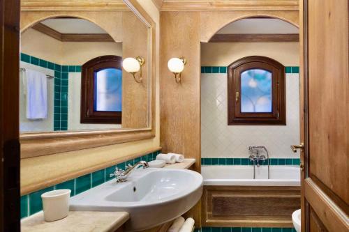 ein Badezimmer mit einem Waschbecken, einer Badewanne und einem Spiegel in der Unterkunft Apartment in Liscia di Vacca - Sardinien 43449 in Liscia di Vacca