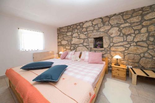 sypialnia z dużym łóżkiem i kamienną ścianą w obiekcie Holiday home in Tribalj 43209 w mieście Tribalj