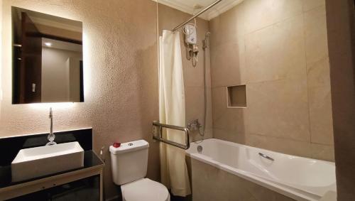 a bathroom with a toilet and a sink and a mirror at Grand Emilia Hotel in Cebu City