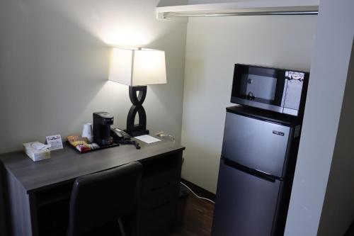 a room with a desk with a refrigerator and a lamp at Timberland Inn & Restaurant in Swan River