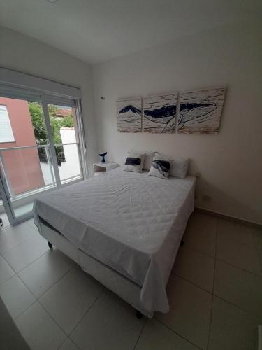 a bedroom with a large bed and a large window at Pé na areia em Boiçucanga condominio Aquamarine - perto de Maresias e Camburi in Boicucanga
