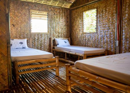 a room with two beds and a bench in it at Ocean Green Eco Lodge in Puerto Princesa City