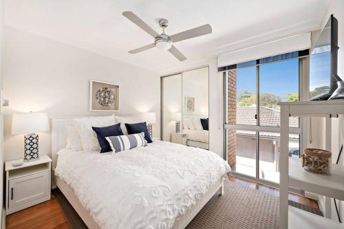 a bedroom with a white bed with a ceiling fan at The Crest in Shoal Bay