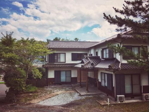 a large house with trees in front of it at 湯布院我楽珍民泊Yufuin Garakuchin in Yufuin