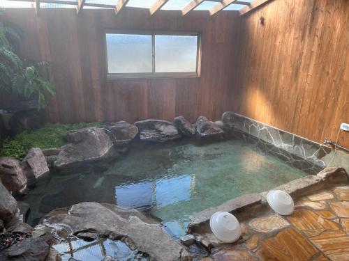 a large pool of water with rocks in a house at 湯布院我楽珍民泊Yufuin Garakuchin in Yufuin