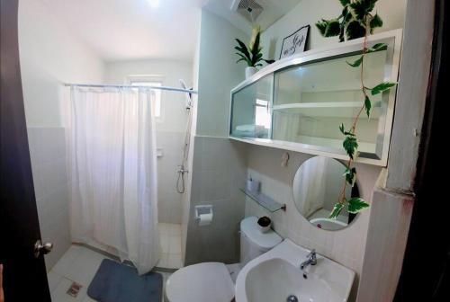 a bathroom with a toilet and a sink and a mirror at Mesaverte Deluxe Studio with Balcony in Cagayan de Oro