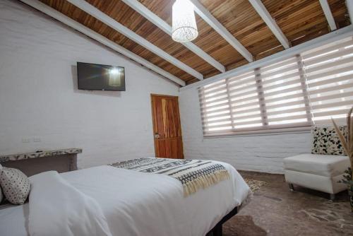a bedroom with a bed and a tv and a chair at Rústic Quinta La Aurora in Baños