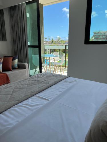 een slaapkamer met een bed en uitzicht op een balkon bij Mana Beach Sol by Vivere Flats in Porto De Galinhas