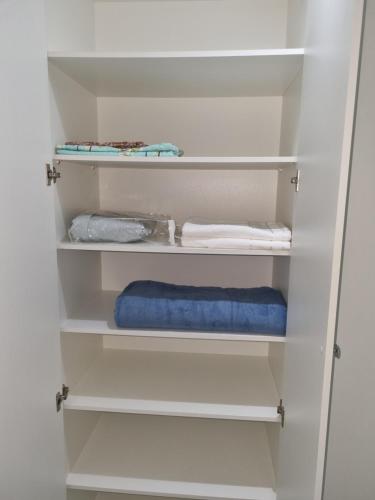 un armario con estanterías blancas y una toalla azul en Espetacular Flat Miramar 4, en João Pessoa