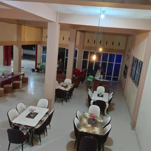 um restaurante com mesas e cadeiras num quarto em Kopay Hotel and Resto em Payakumbuh
