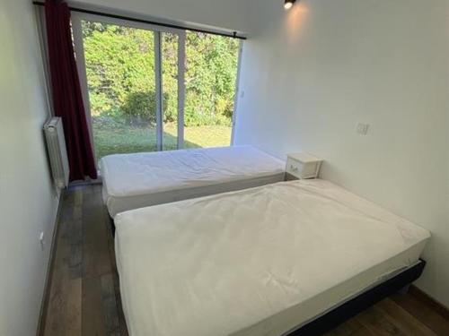 deux lits dans une chambre avec une fenêtre dans l'établissement Maison au cœur de La Brée-les-Bains - 6 couchages, jardin clos, proche plage, WiFi gratuit - FR-1-246A-156, à La Brée-les-Bains