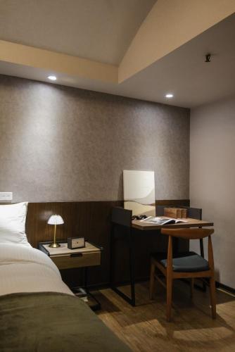 a bedroom with a bed and a desk with a lamp at Giant Rich Hotel in Taipei
