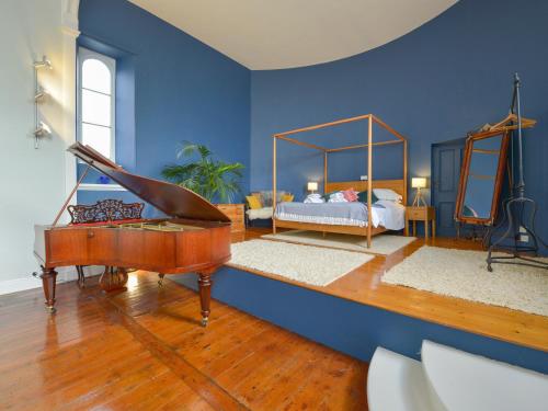 een blauwe kamer met een bed en een piano bij The Music Room in Aveton Gifford