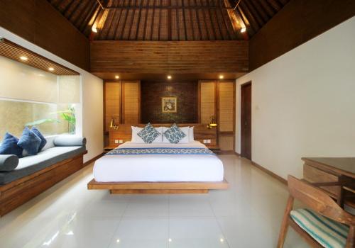 a bedroom with a large white bed and a bench at Sagara Villas and Suites Sanur in Sanur