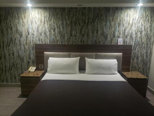 Motel Nuevo Tijuana في مدينة ميكسيكو: غرفة نوم بسرير كبير مع مواقف ليلتين