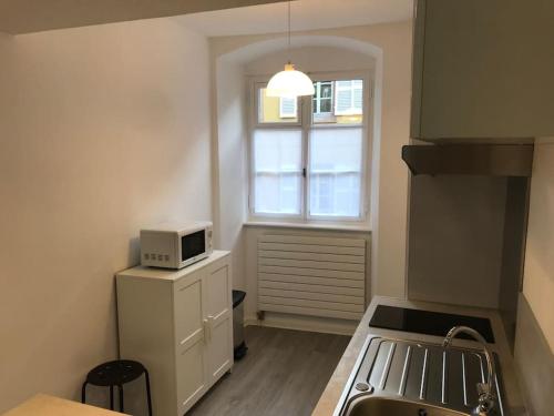 une petite cuisine avec un micro-ondes au-dessus d'un réfrigérateur dans l'établissement Le Johannes-Colmar centre historique, à Colmar
