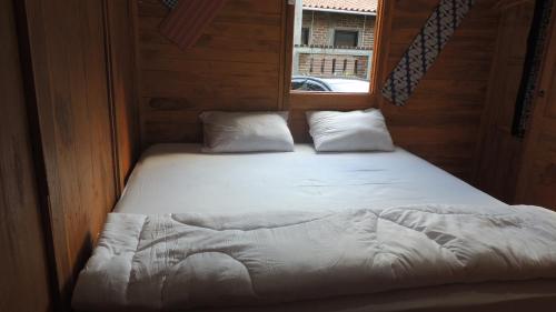 Bett in einem kleinen Zimmer mit Fenster in der Unterkunft Omah Rumba Bata in Ngemplak