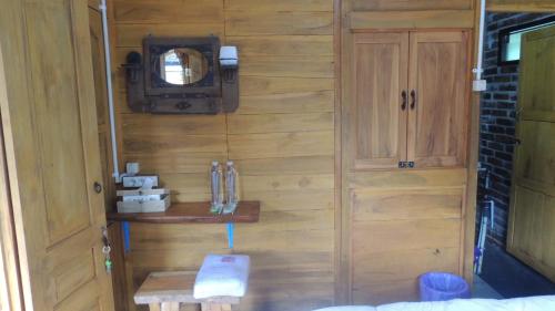 Zimmer mit einer Holzwand und einem Spiegel in der Unterkunft Omah Rumba Bata in Ngemplak