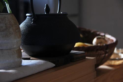 a black vase sitting on a table with a basket at 淡路島西海岸の宿 梅木屋 in Sumoto