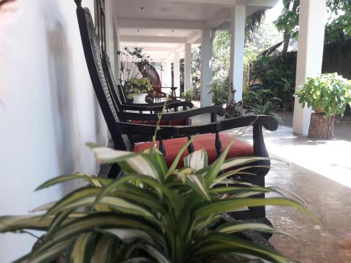 a porch with two black chairs and a plant at Sea Front Hikkaduwa in Hikkaduwa