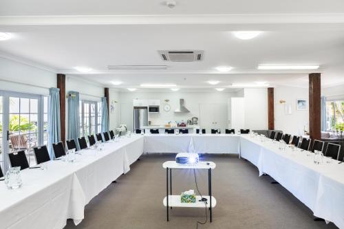 a dining room with white tables and black chairs at Northridge Golf Resort in Orewa