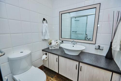 a bathroom with a toilet and a sink and a mirror at 65 @ Zeezicht in Kingsburgh